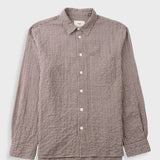 A long-sleeve button-up shirt with a small-scale brown and white checkered pattern, featuring a classic collar, white buttons, and a chest pocket, displayed against a light gray background.