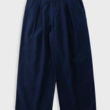 Navy trousers with large front pleat, against a light grey background