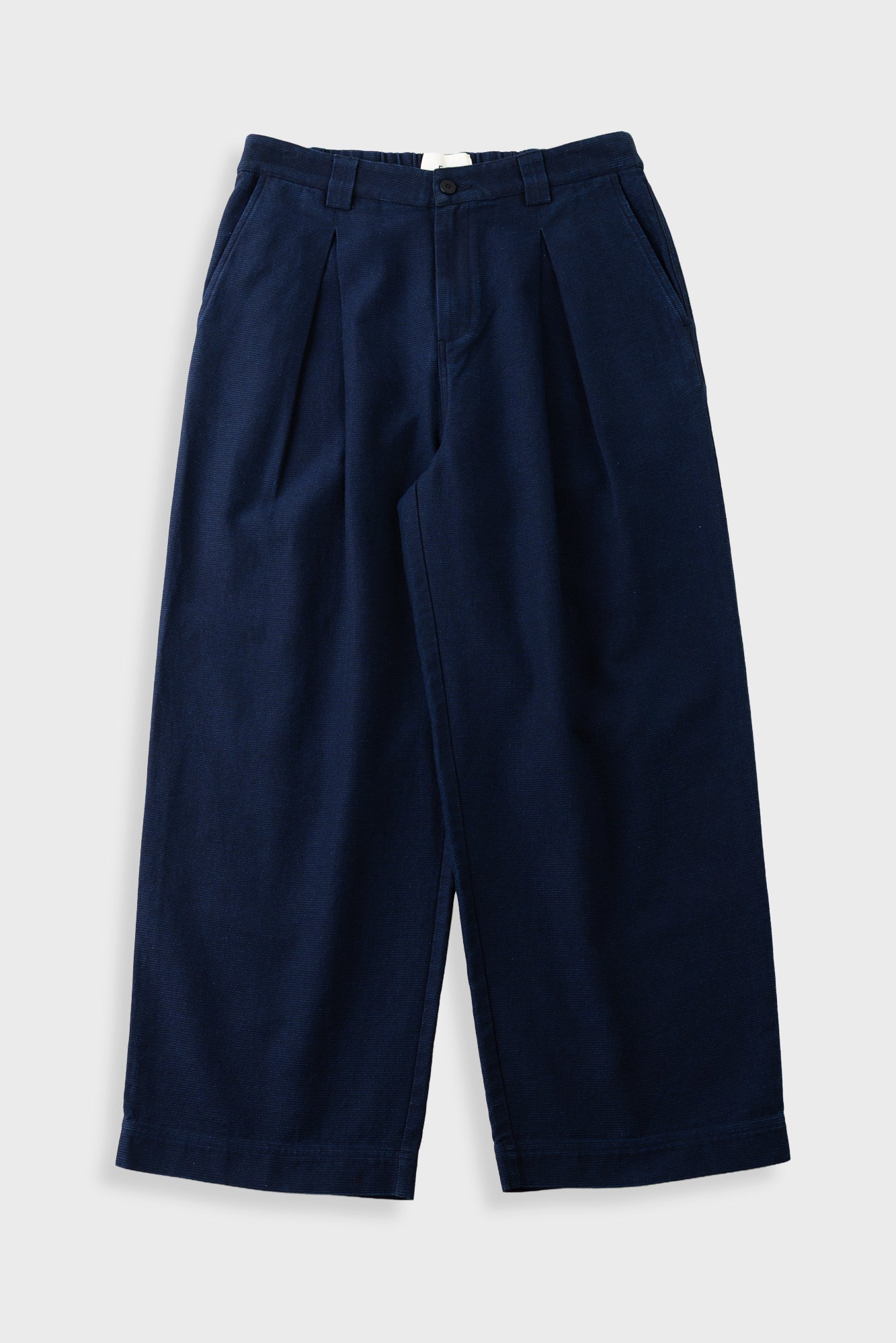 Navy trousers with large front pleat, against a light grey background