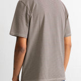 A man wearing a short-sleeve crewneck t-shirt with thin horizontal brown and beige stripes, shown from the back against a plain white wall.