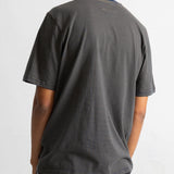 A man viewed from behind wearing a dark green and black horizontally striped t-shirt and dark jeans against a plain white background.