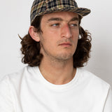 Man wearing a plaid cap and white shirt against a plain background