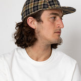 Man wearing a plaid cap and white sweatshirt against a plain background