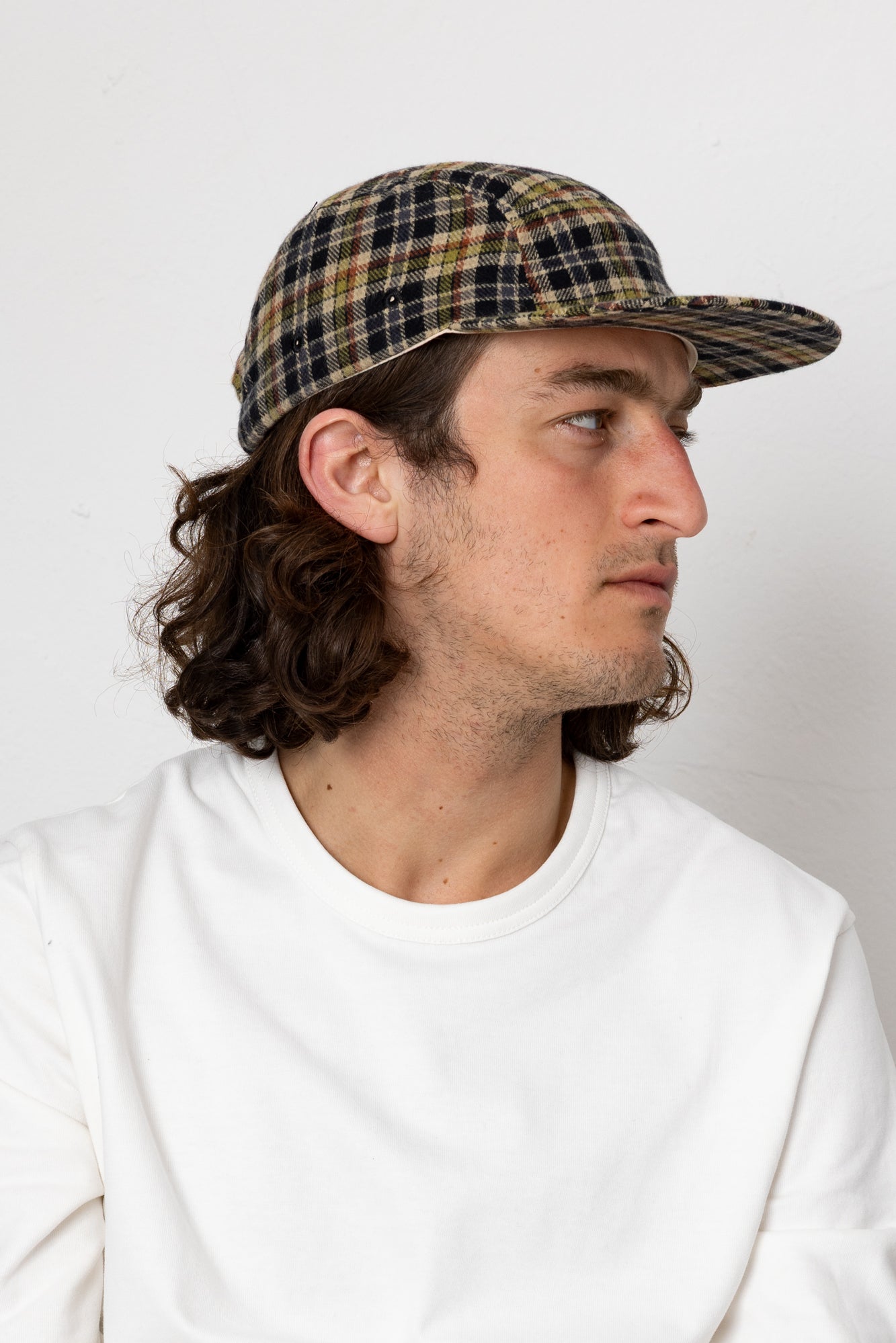 Man wearing a plaid cap and white sweatshirt against a plain background
