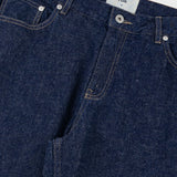 Close-up of blue denim jeans with a visible brand label on a light gray background