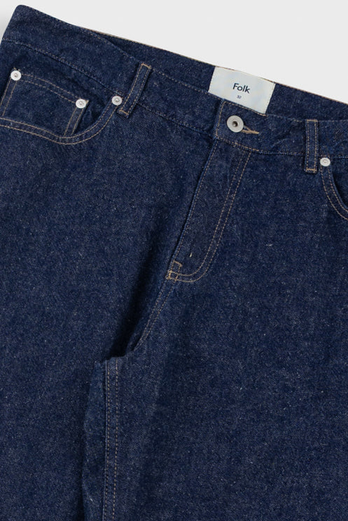 Close-up of blue denim jeans with a visible brand label on a light gray background