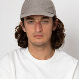 Man wearing a gray cap and white shirt against a plain background
