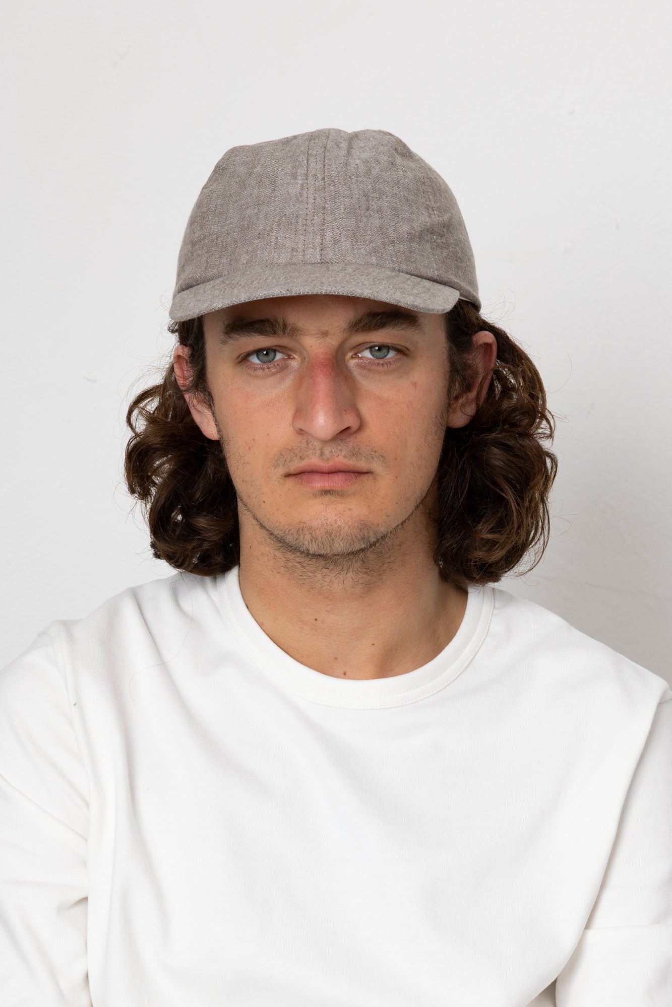 Man wearing a gray cap and white shirt against a plain background