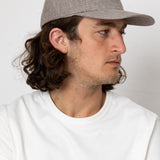 Man wearing a gray cap and white shirt against a plain background