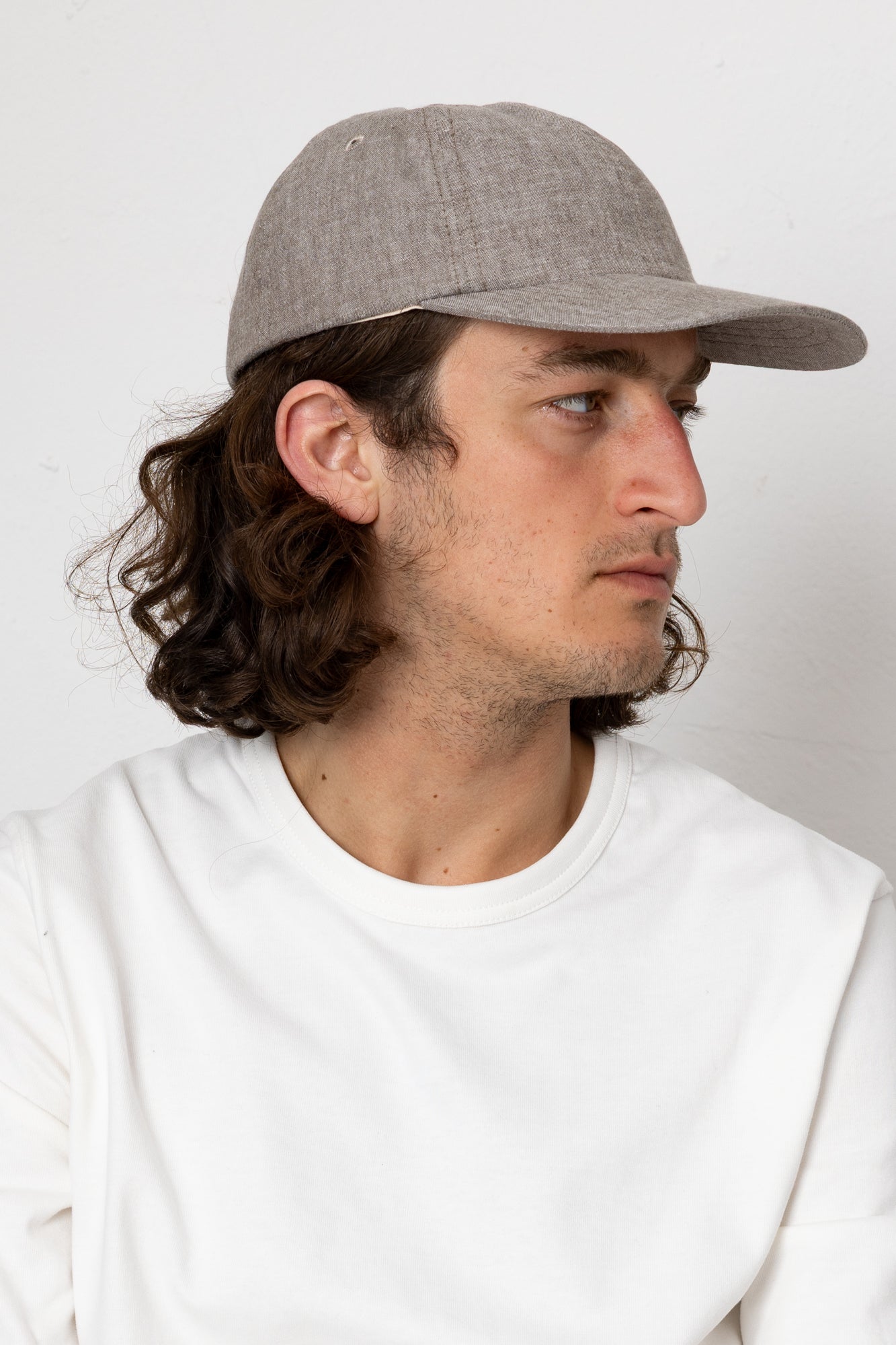Man wearing a gray cap and white shirt against a plain background