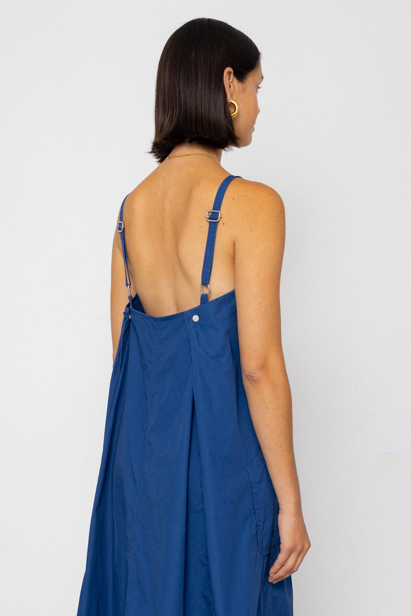 Woman wearing a blue dress with thin straps on a white background