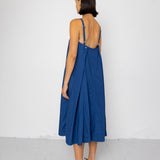 Woman wearing a blue dress with an open back against a white background