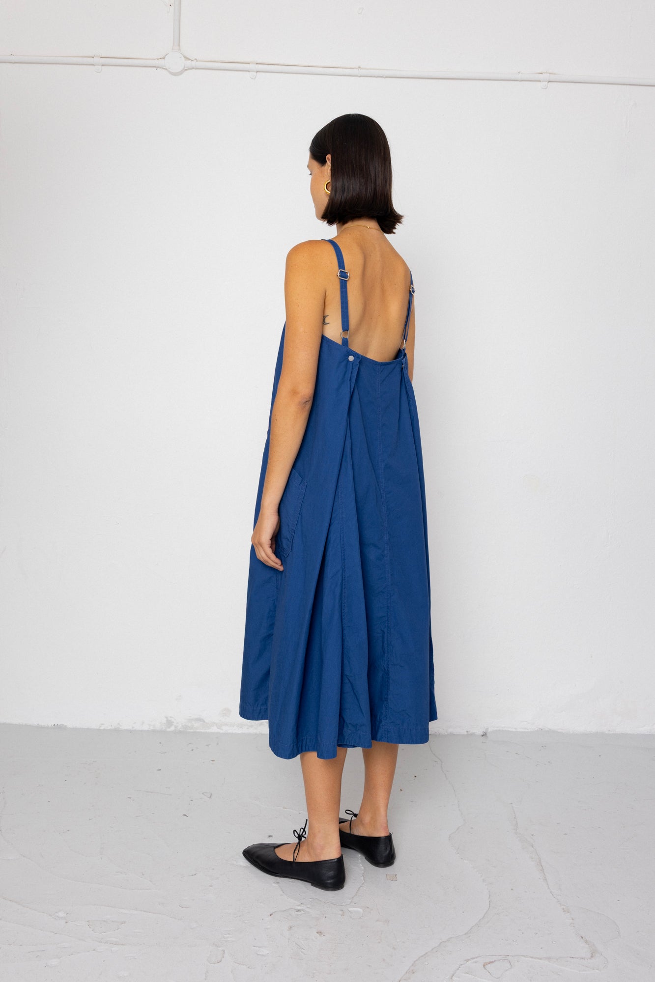 Woman wearing a blue dress with an open back against a white background