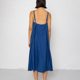 Woman wearing a blue dress with thin straps against a white background