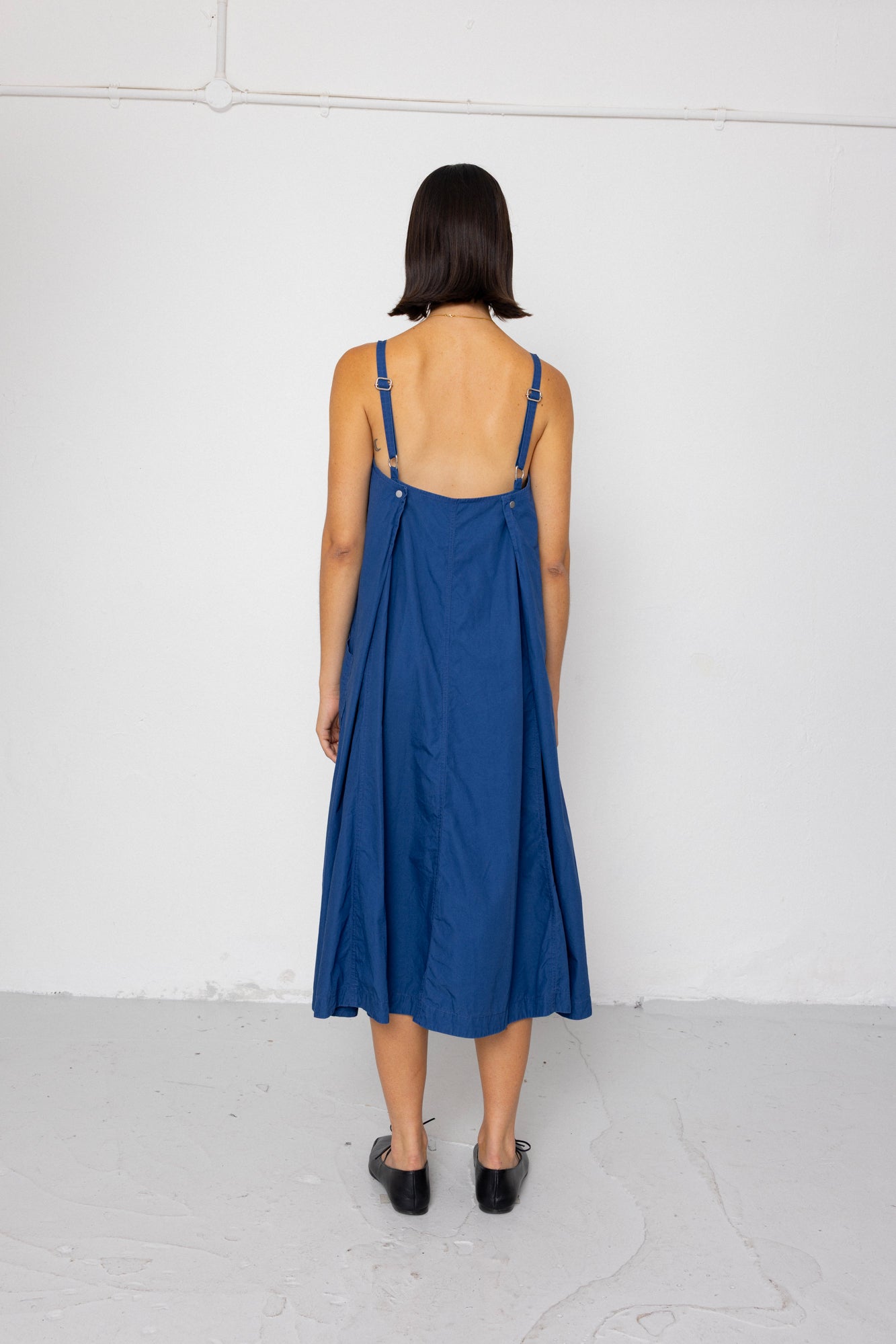 Woman wearing a blue dress with thin straps against a white background