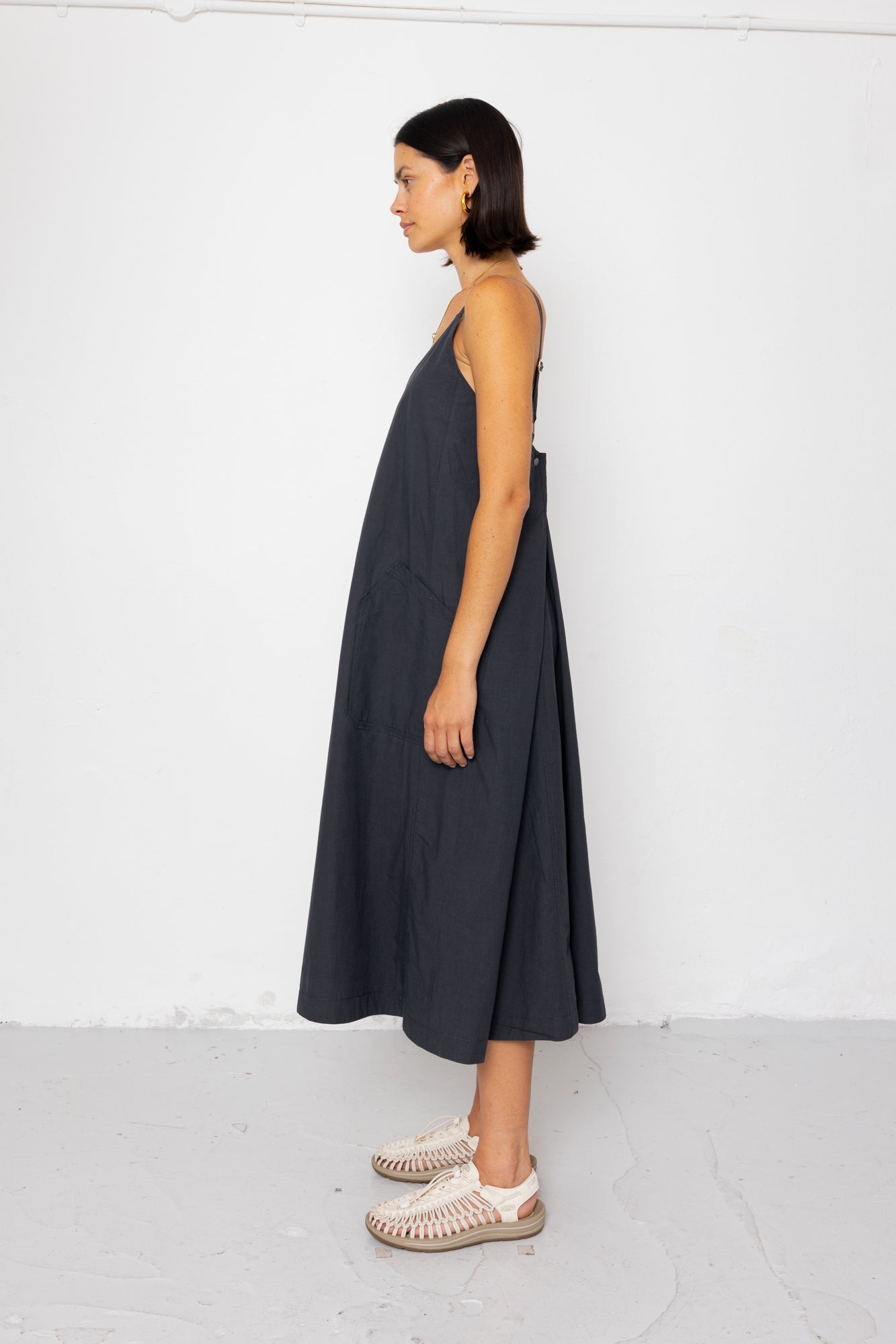 Woman wearing a dark gray dress standing against a white background