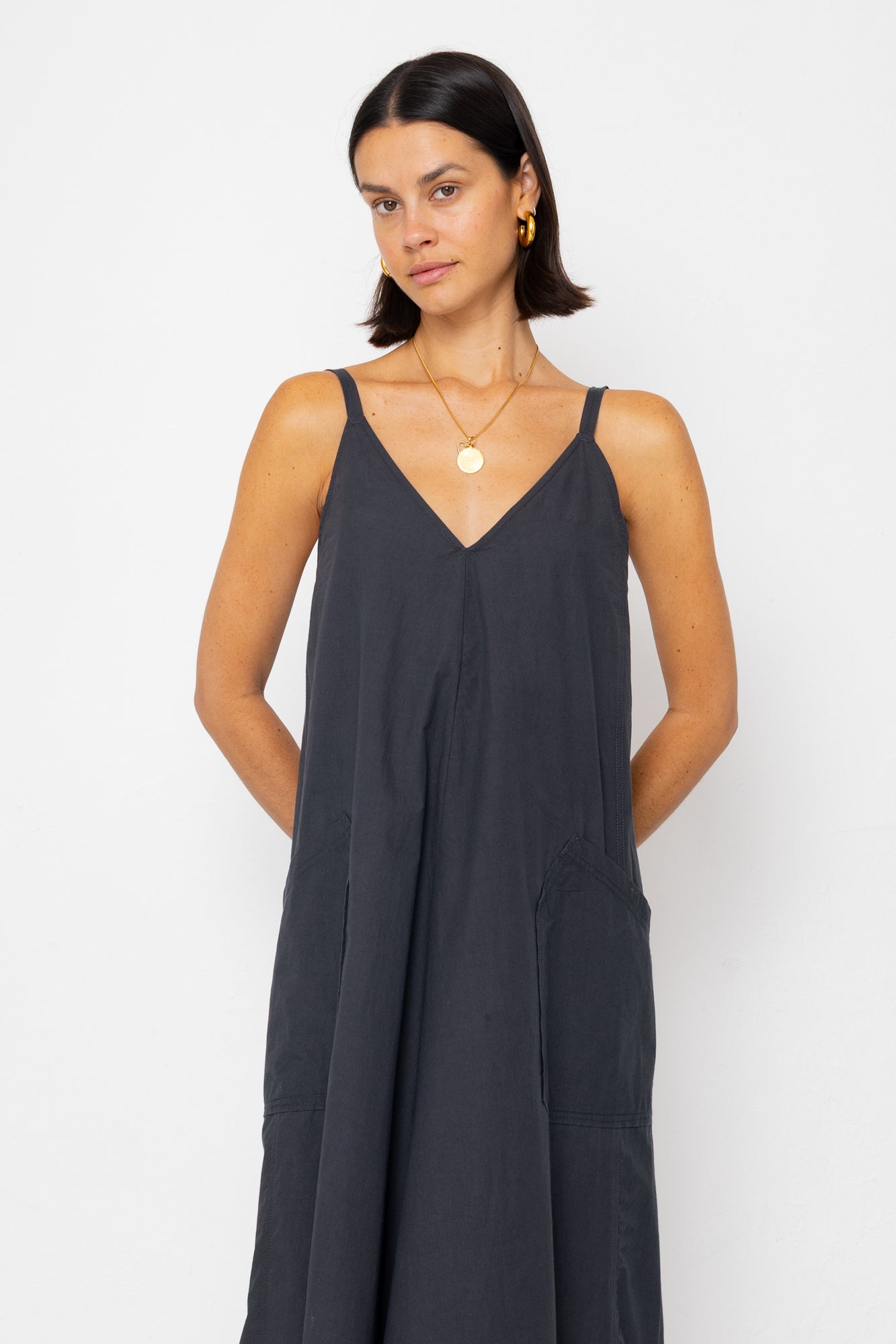 Woman wearing a black slip dress against a white background