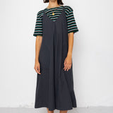 Woman wearing a striped shirt and black dress against a white background