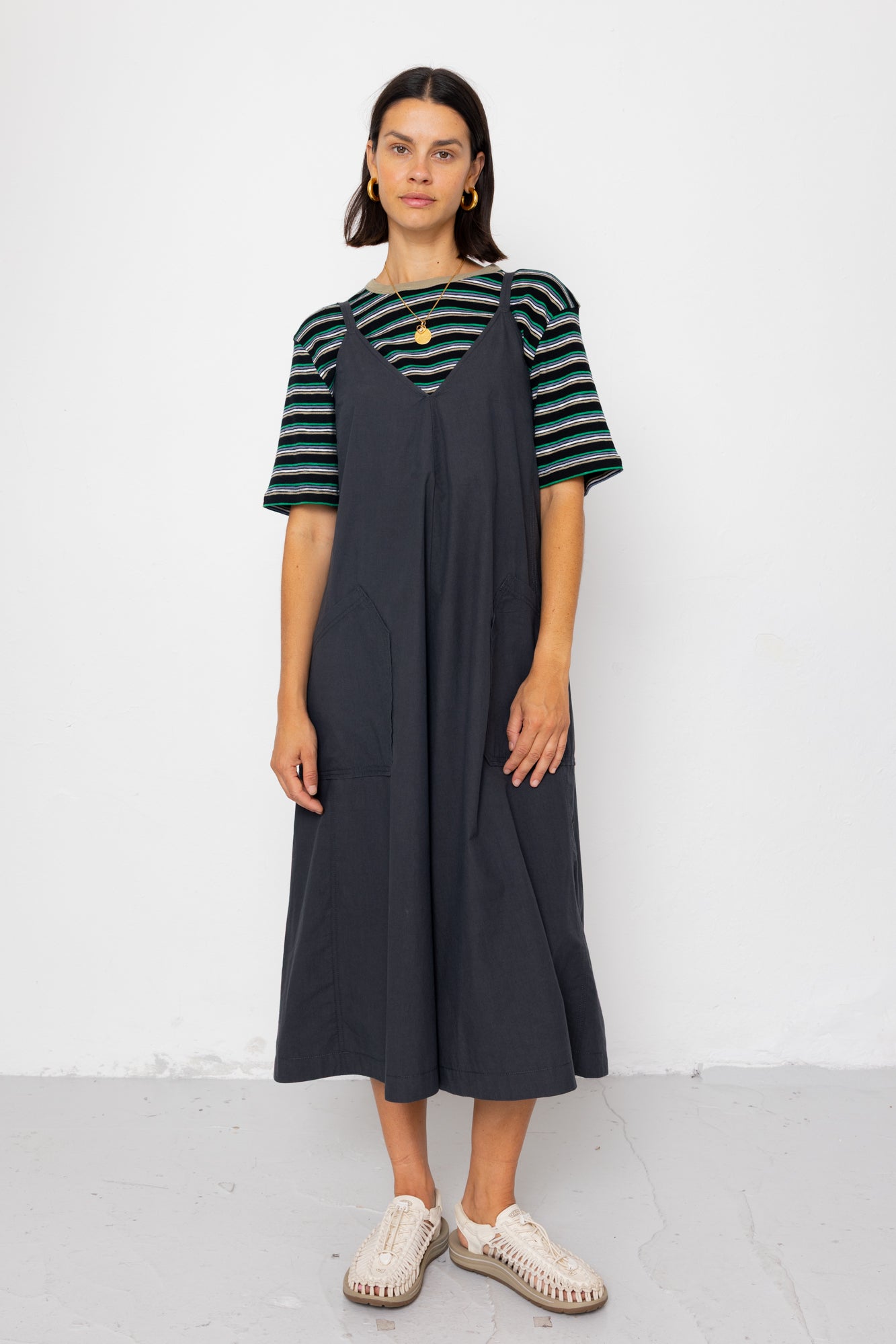 Woman wearing a striped shirt and black dress against a white background