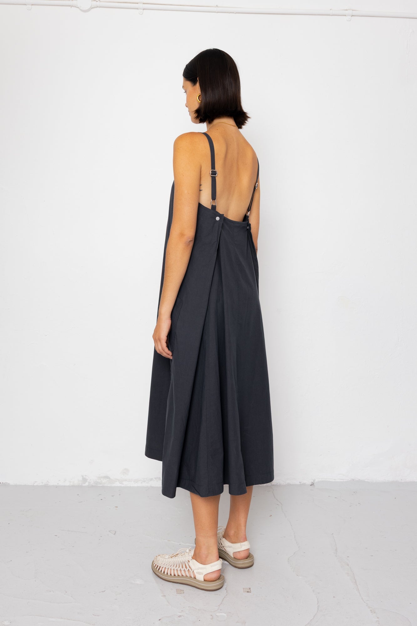 Woman wearing a black dress with thin straps against a white background