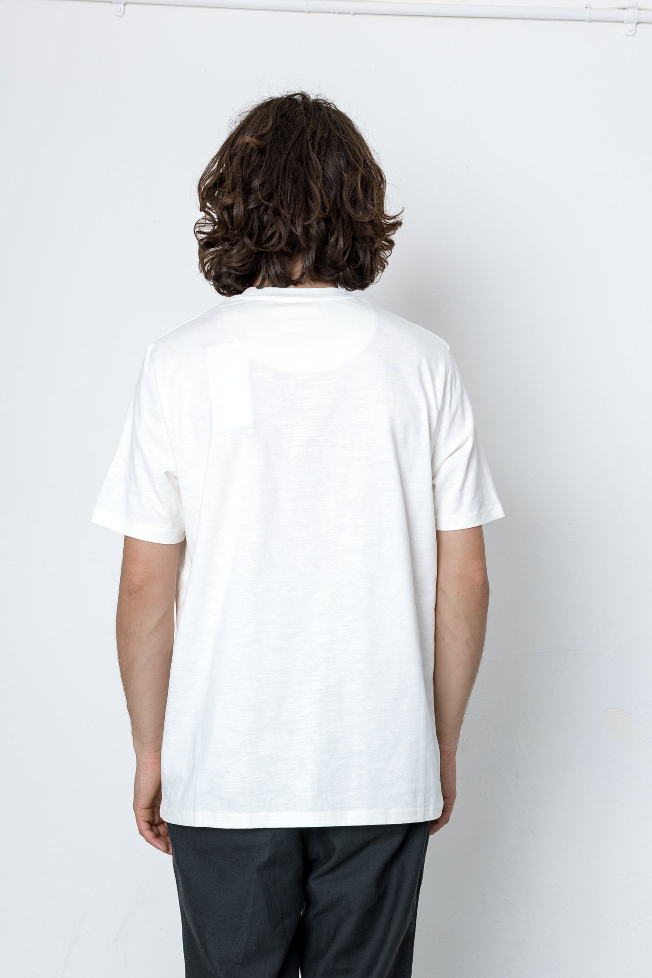 Person wearing a plain white t-shirt against a white background