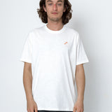Person wearing a white t-shirt with a small logo on a plain background