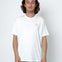 Person wearing a white t-shirt with a small logo on a plain background