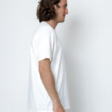 Man wearing a plain white t-shirt against a white background
