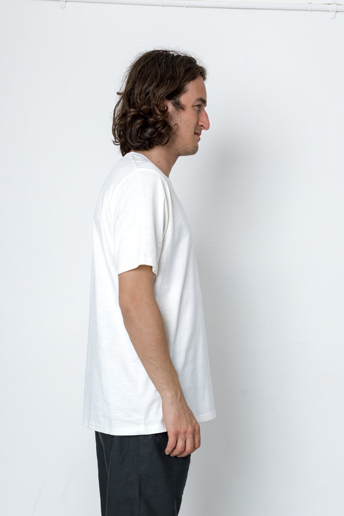 Man wearing a plain white t-shirt against a white background