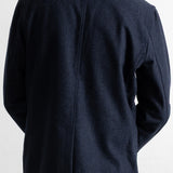 Back view of a person wearing a dark navy blazer over a white collared shirt, shown against a plain light background.