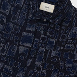 Close-up of a dark blue patterned shirt with a brand label on a light gray background