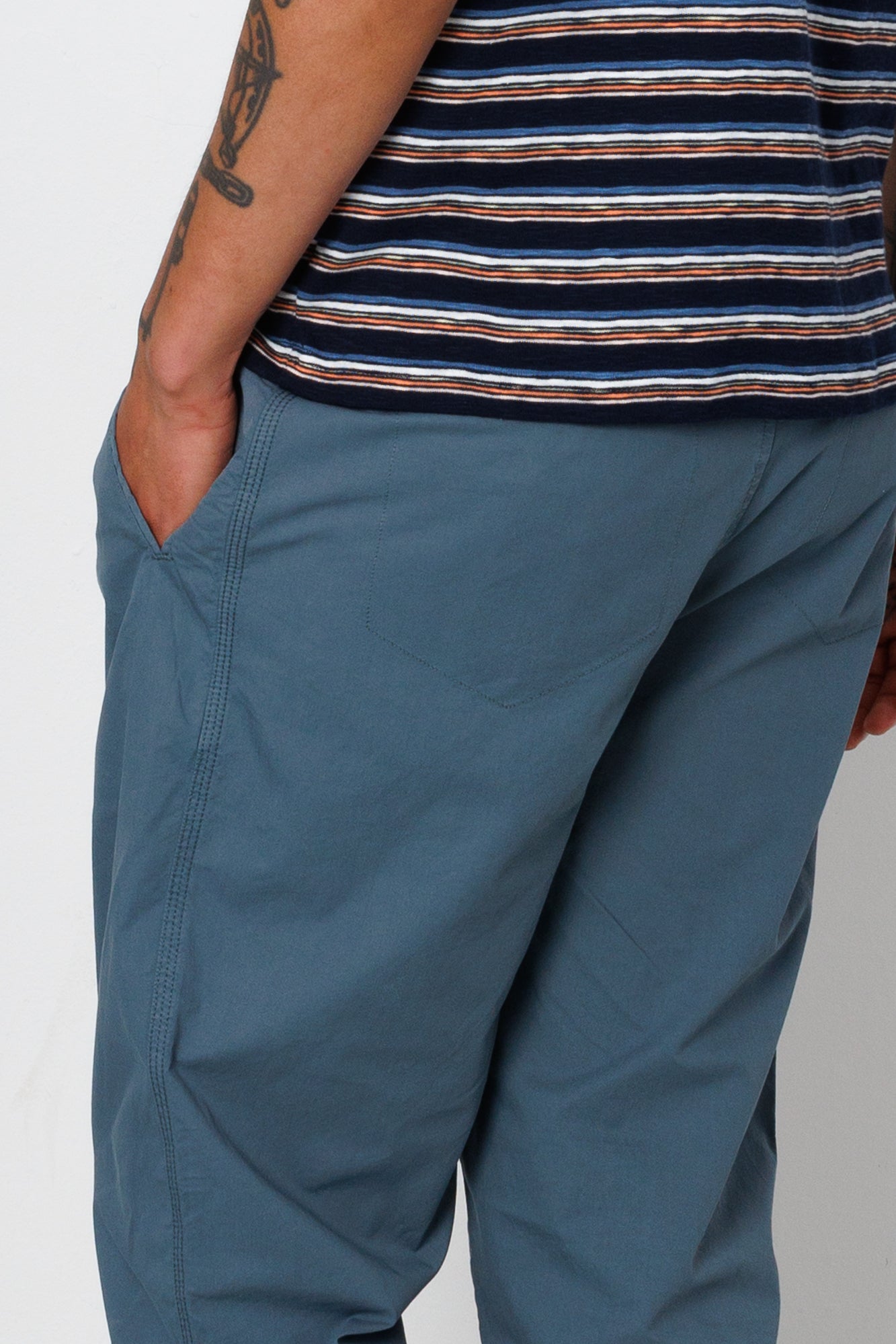Person wearing blue pants and a striped shirt on a plain background