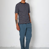 Man wearing a striped shirt, blue pants, and black sneakers against a white background