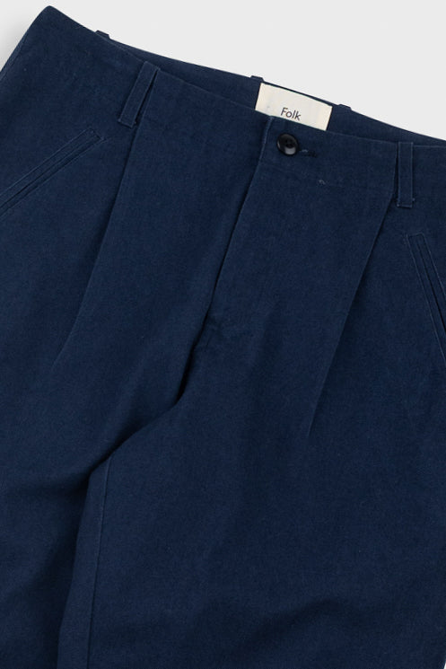 Navy blue pleated pants with a visible brand label on a white background