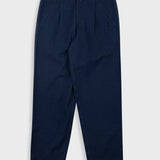 Navy blue pleated pants with a visible brand label on a white background