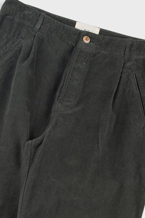 Dark green pleated pants with a close-up on the waistband and pleats.