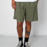 Person wearing green shorts and black high-top sneakers on a white background
