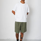Man wearing a white t-shirt and green shorts standing against a white background