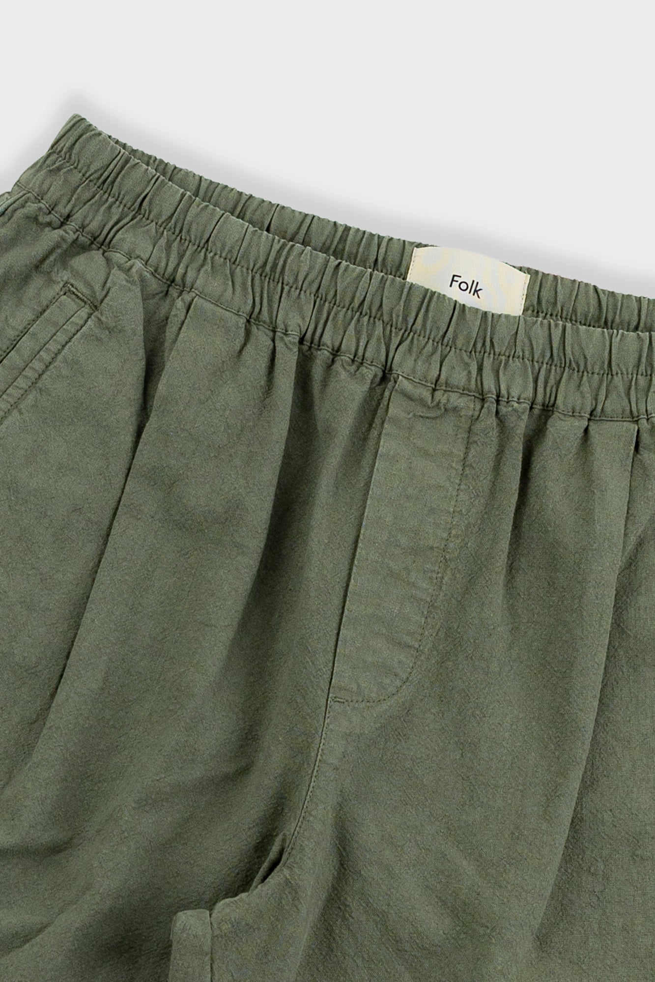 Green pants with an 'Folk' label on a light gray background