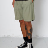 Person wearing green shorts and black high-top sneakers on a white background