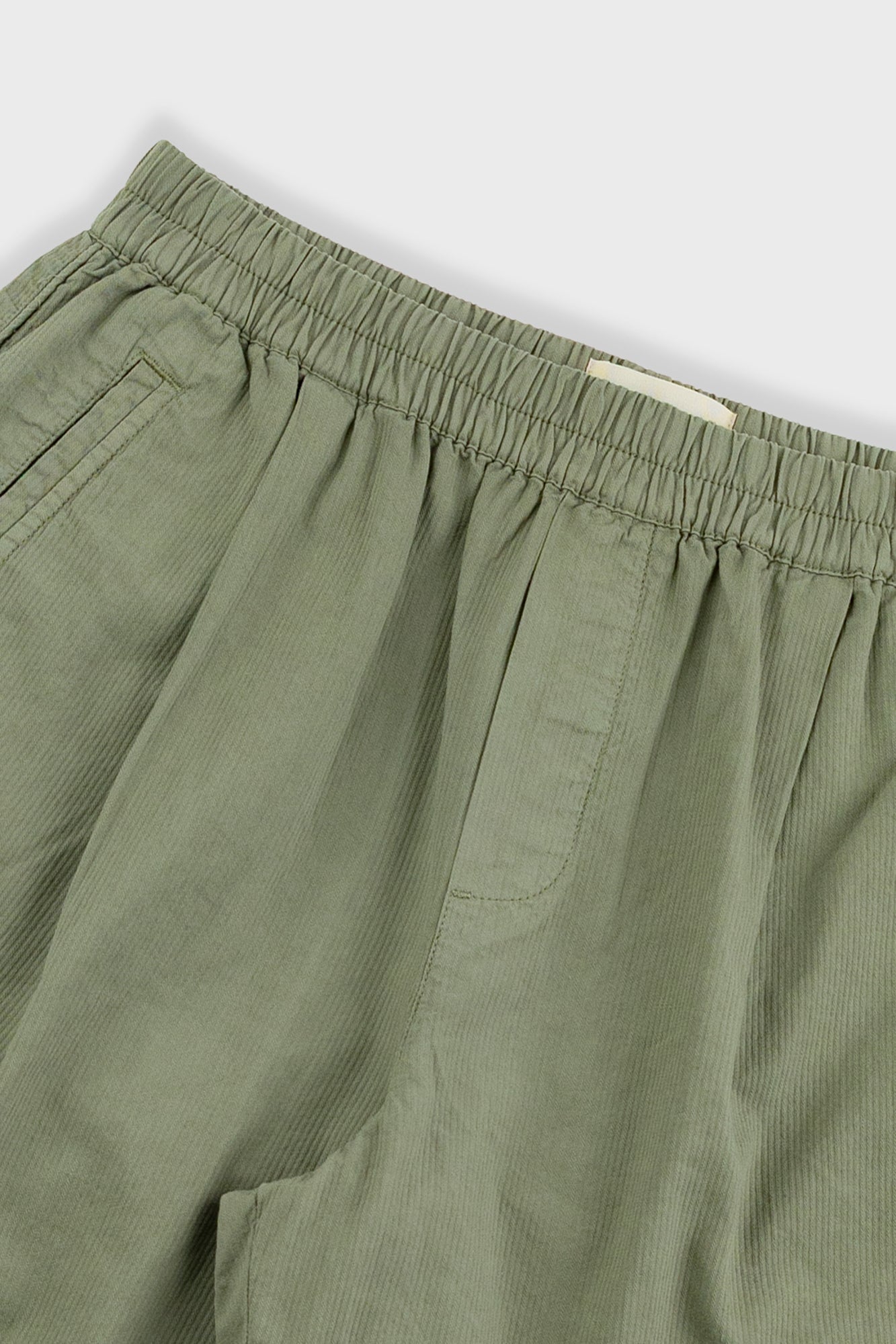 Close-up of green pants with an elastic waistband on a light gray background