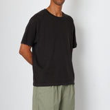 Man wearing a black t-shirt and green shorts against a white background