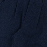 Navy blue pleated pants with a visible brand label on a light background