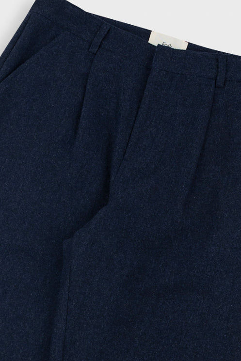 Navy blue pleated pants with a visible brand label on a light background