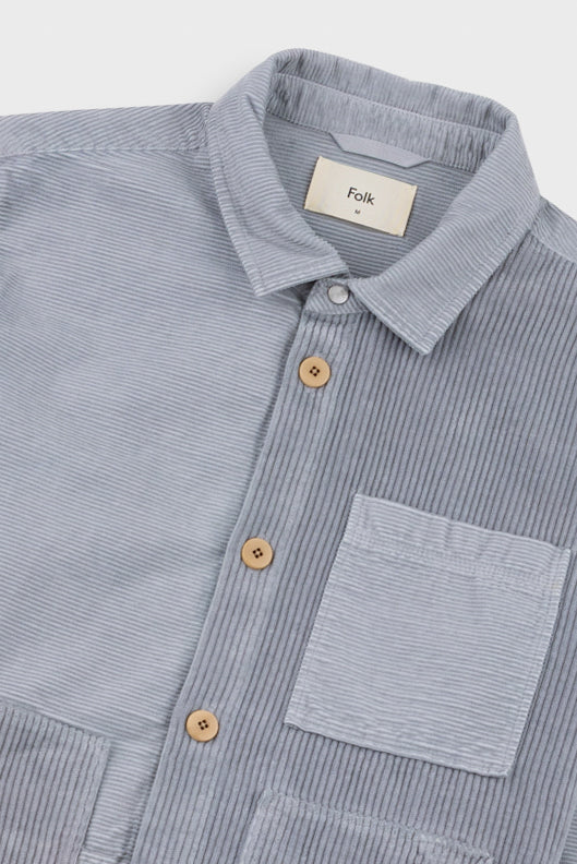 Gray striped shirt with wooden buttons and a visible brand label on a light gray background