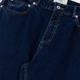 Close-up of dark blue jeans with a visible brand label on a white background