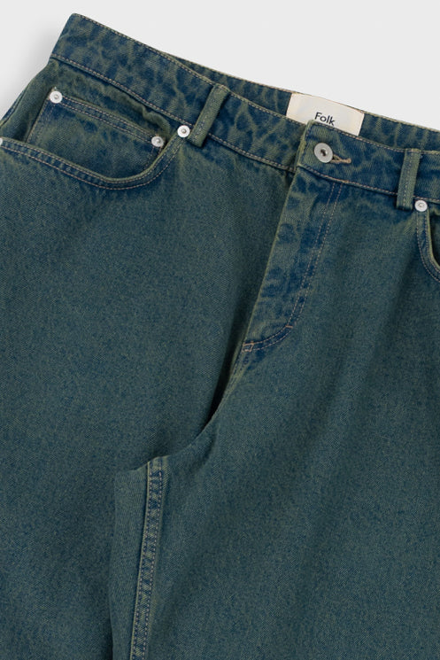 Close-up of green denim jeans with a brand label on a white background