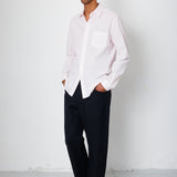 Man wearing a white shirt and black pants against a white background