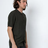 Man wearing a dark green patterned shirt against a white background