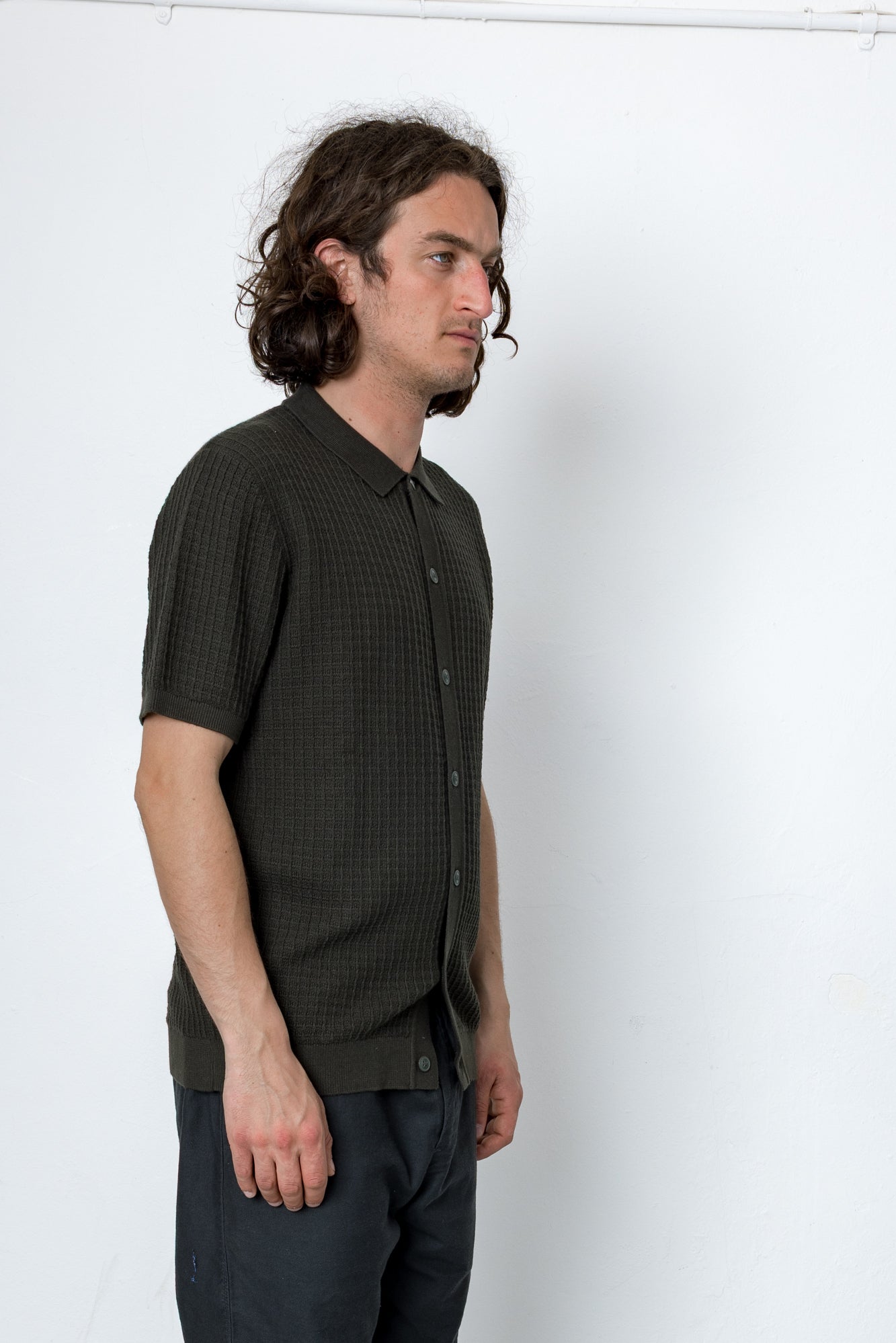 Man wearing a dark green patterned shirt against a white background